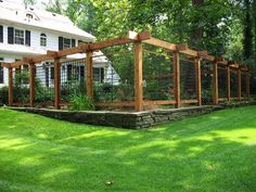 a fenced in garden area with grass and rocks on the ground near a house