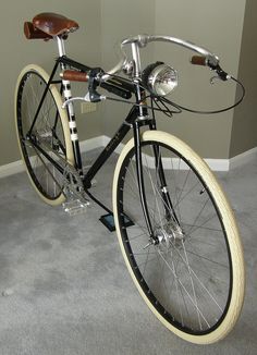 a black and white bicycle parked on top of a carpeted floor next to a wall