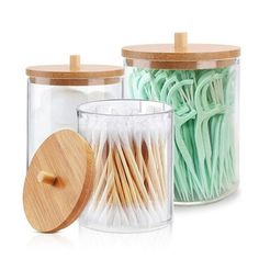 two glass jars with wooden lids filled with cotton swabs