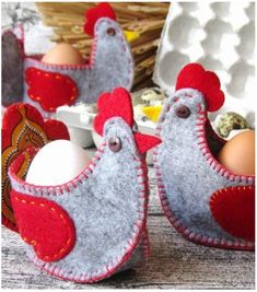 two eggs are in an egg carton with red felt chickens on the top and one chicken is standing next to it