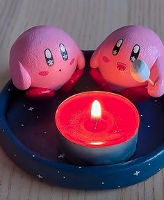 two stuffed animals sitting on top of a plate with a lit candle in front of them