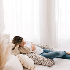 a woman laying on top of a bed covered in pillows