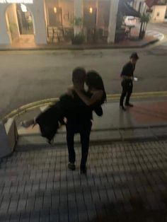 two people hugging each other on the side walk at night, with one person walking down the street