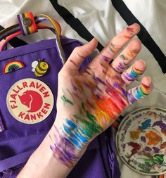 a person's hand with colorful paint on it next to a plate and bag