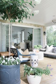 an outdoor living room with potted plants on the porch