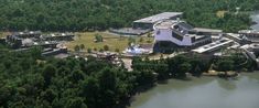 an aerial view of a large building surrounded by trees and other buildings near the water