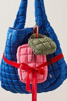 a blue and pink handbag with a red ribbon around the strap, hanging from a hook