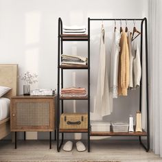 an open closet with clothes hanging on the rack and shoes in baskets next to it