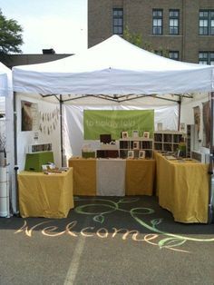 a white tent with yellow and green tables under it