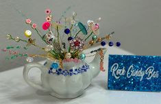 a white teapot filled with lots of assorted items next to a blue box