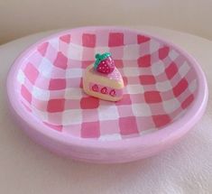 a pink and white checkered plate with a small piece of cake on the edge