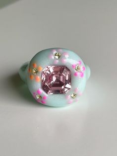 Hand sculpted soft light blue polymer ring with floral print hand painted and smaller crystals with elegant rose pink main crystal in the middle Pink Hand Painted Resin Jewelry, Hand Painted Pink Resin Jewelry, Handmade Pink Resin Rings, Polymer Ring, Ice Blue Color, Floral Artwork, Soft Light, Rose Pink, Ice Blue