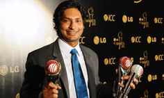 a man in a suit and tie holding three awards