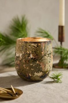 a wooden bowl sitting on top of a table next to a candle and some plants