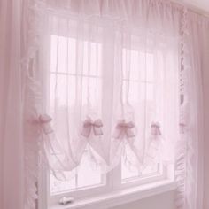 a window with sheer curtains and pink bows on the valance, in front of a white radiator