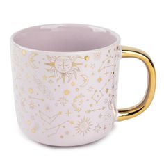 a white and gold coffee mug with stars, moon and sun designs on the side