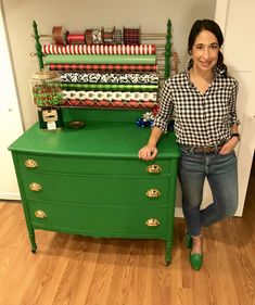 a woman standing next to a green dresser