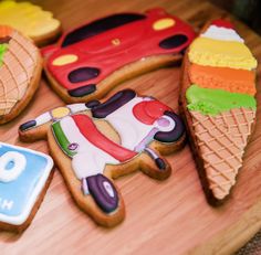 decorated cookies are arranged on a wooden platter with cars and ice cream cones in the background