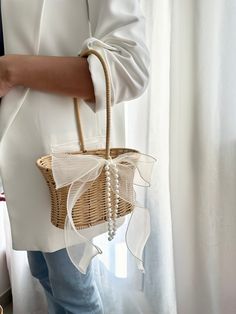 a woman is holding a wicker basket with pearls on it and wearing blue jeans