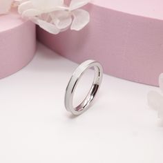 a wedding ring sitting on top of a pink box next to flowers and a flower