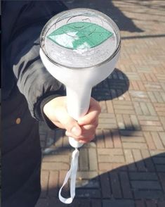 a person holding a white hair dryer with a green leaf on it's top