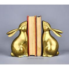 a bookend made out of gold colored metal with two rabbits sitting next to each other