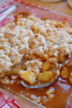 a glass dish filled with apple cobbler on top of a red and white checkered table cloth