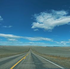 an empty highway stretches into the distance with blue skies and clouds in the background on a sunny day