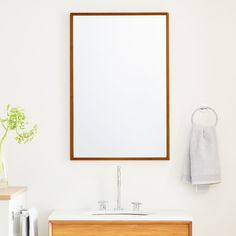 a bathroom with a sink, mirror and towel on the wall next to a cabinet