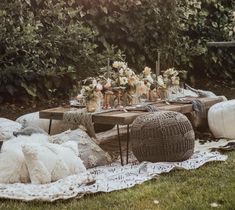 a picnic table with flowers and candles on it in the middle of a grassy area