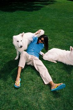 a person laying on the grass with two dogs