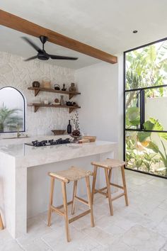 a kitchen with two stools next to an island counter and open shelves on the wall