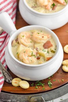 two white bowls filled with shrimp chowee on top of a cutting board next to crackers