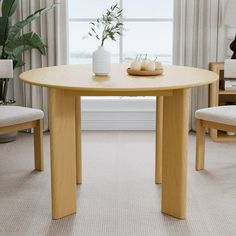 a wooden table sitting in front of a window next to two chairs and a potted plant