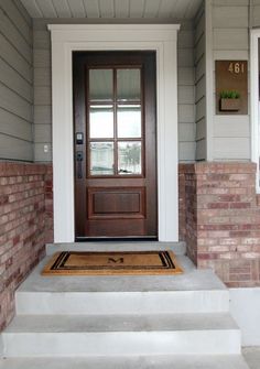 the front door of a house with steps leading up to it and a welcome mat