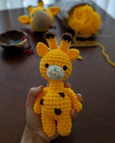 a crocheted giraffe is being held up by someone's hand