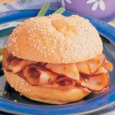 a sandwich with ham and cheese on a bun sits on a plate next to some vegetables