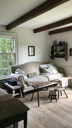 a living room filled with furniture next to a window and wooden floored flooring