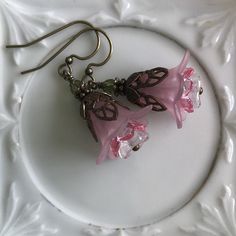 "Pretty in Pink... Add some spring to your wardrobe with these lovely double pink blossoms. Delicate pink petals surround bright pink and white centers. Antique brass filigree caps adorn the tops and a tiny green bead adds a bit of spring pop. These earrings are very lightweight and comfortable to wear. Perfect for a garden wedding, or a gift for a nature lover. And don't forget...Mother's Day is just around the corner. Drop length from bottom of antique brass french earwire: 1\" (25mm) Prefer a Pink Handmade Flower Earrings For Spring, Pink Earrings With Handmade Flowers For Spring, Pink Earrings With Handmade Flowers For A Gift, Nickel Free Pink Flower Earrings, Pink Earrings With Ear Wire For Spring, Adjustable Pink Jewelry With Handmade Flowers, Pink 3d Flowers Jewelry For Gift, Pink Flower Earrings With Ear Wire For Spring, Pink Flower Earrings For Gift