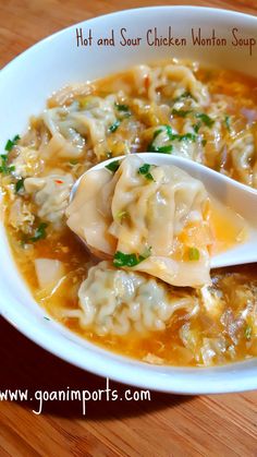 a white bowl filled with soup and dumplings on top of a wooden table next to a spoon