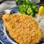 a blue and white plate topped with chicken, rice and broccoli next to a fork