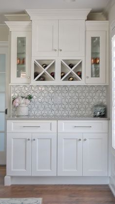 a kitchen with white cabinets and glass front cupboards on the wall, along with hardwood flooring