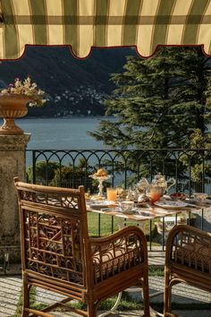 an outdoor dining area with chairs, table and view of the water in the background