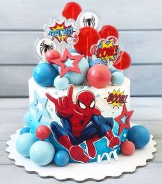 a spiderman cake with balloons and decorations on the top is ready to be eaten