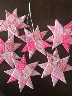 pink and white paper stars are hanging from strings on a wooden table with polka dots