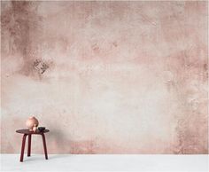 a small table with a vase on it in front of a concrete wall and floor