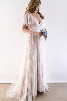 a woman in a white dress is holding a bouquet and looking down at the floor