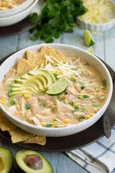 a bowl of chicken quesadilla soup with tortilla chips and avocado