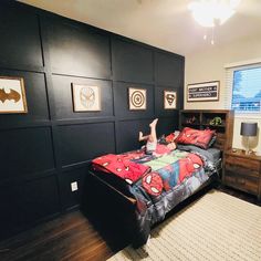 a person laying on top of a bed in a room with black walls and wooden floors