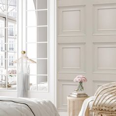 a bedroom with white walls and wicker furniture, flowers in vase on the bed